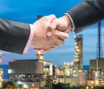 Businessmen hold hands falling oil investment.